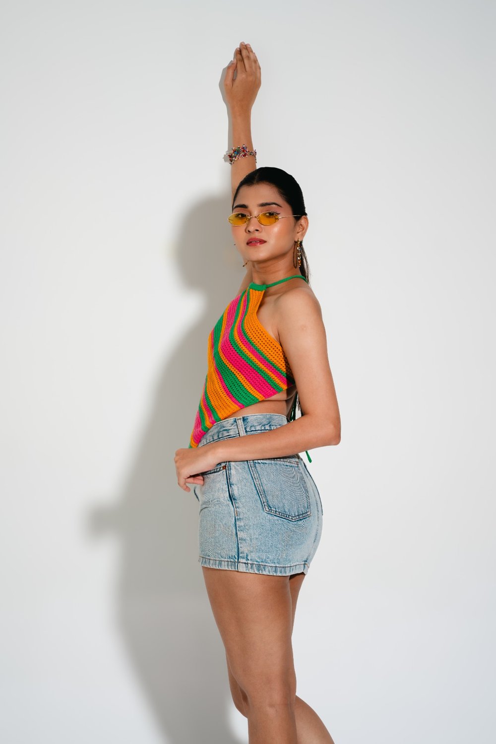 Side angle of Candy Crochet Top paired with denim skirt — bright rainbow crochet summer top