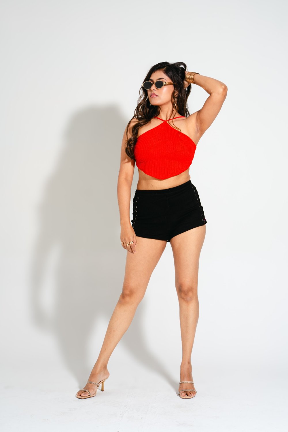 Model kneeling in Gia Sangria Red crochet crop top and black shorts, bold vacation-ready look from Boarding Pass Store