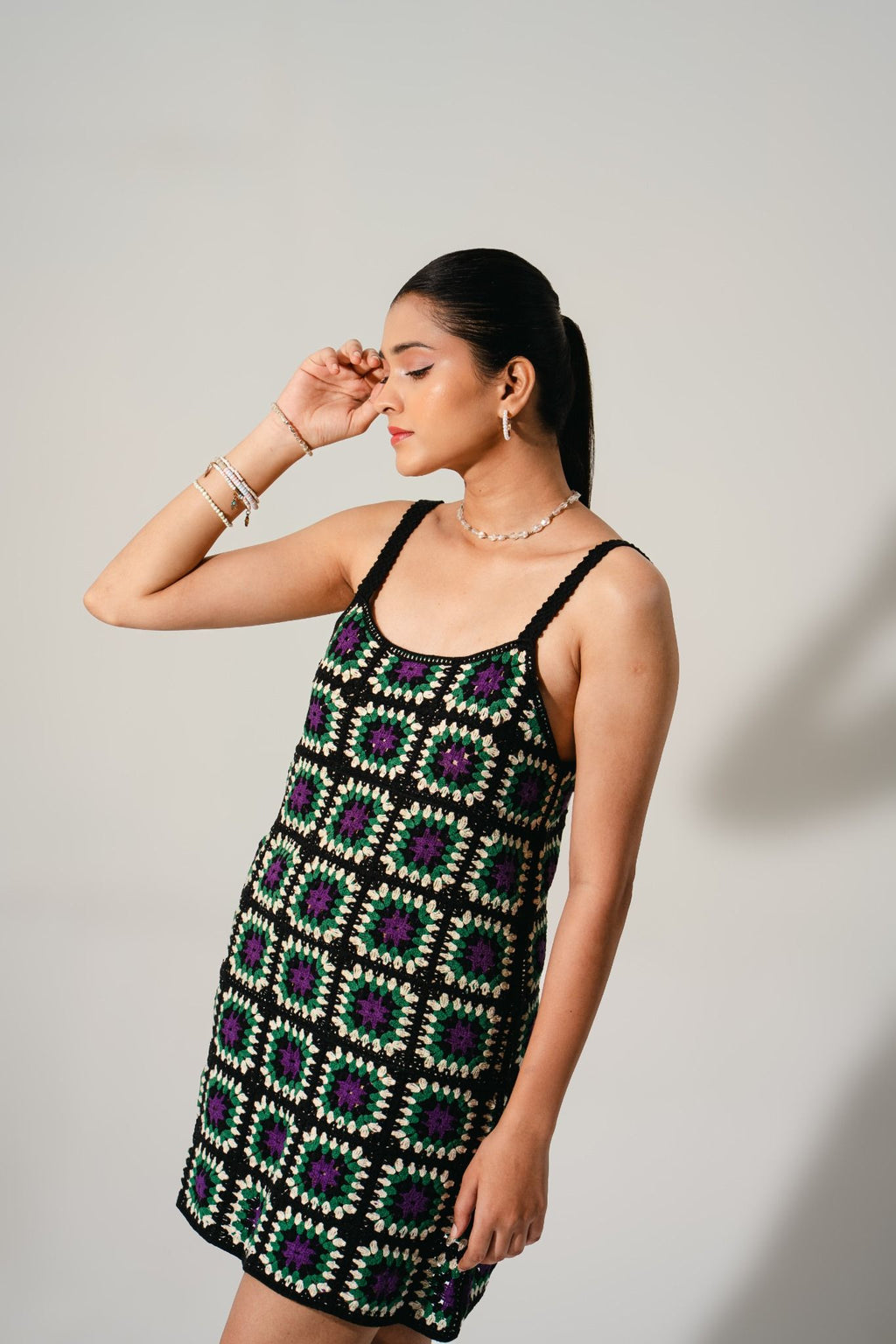 Editorial portrait in Hana Cinder Crochet Mini Dress — handmade black mini dress with green and purple patchwork squares