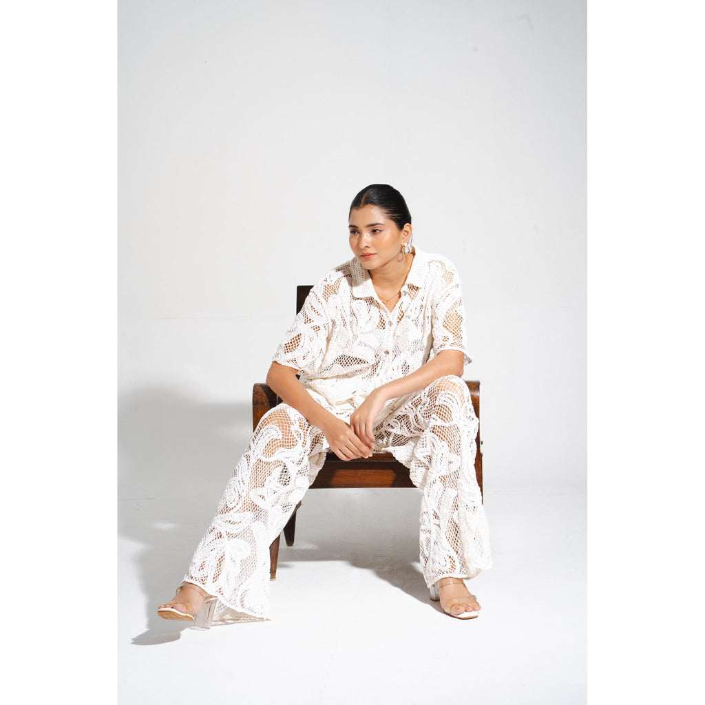 Woman in the Laurel Crochet Full Length Coord Set sitting on a wooden chair, displaying the intricate lace crochet pattern and summer-ready styling